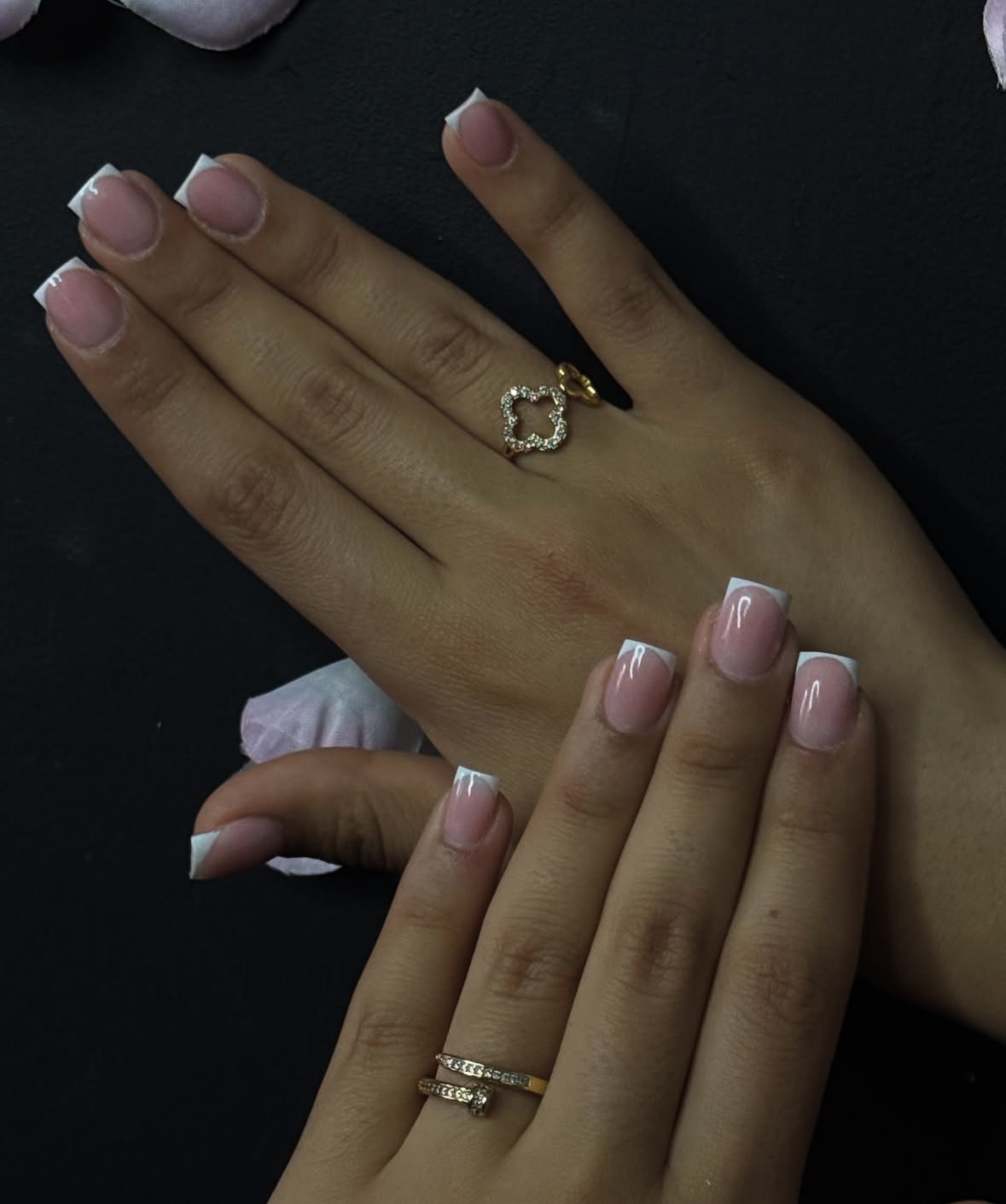 Korte French manicure, twee handen met gouden ringen