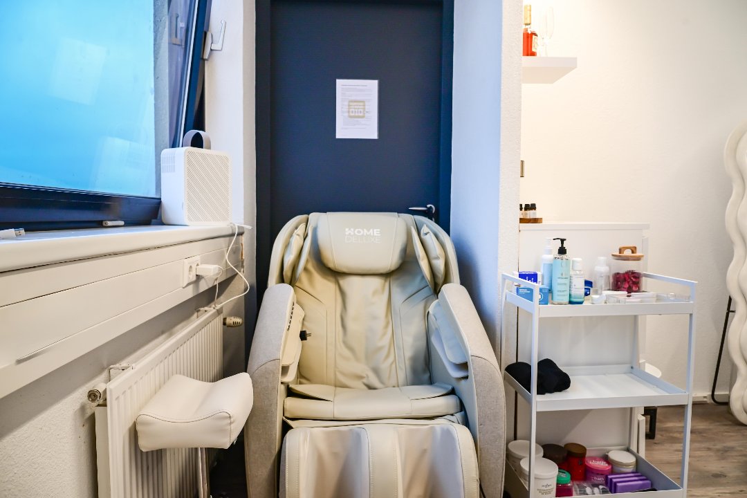 De crèmekleurige massagestoel voor de pedicure, naast het raam